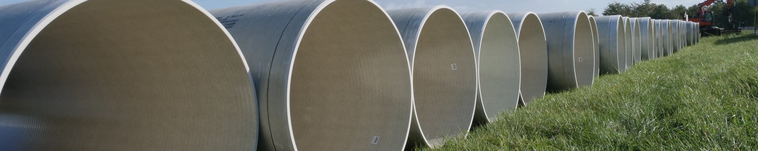 Witte betonnen buizen op een rij in groen gras.
